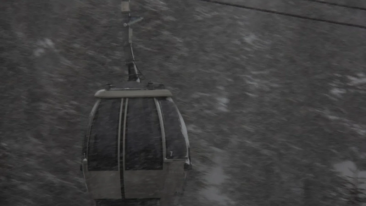 a snow covered ski lift in the middle of a forest